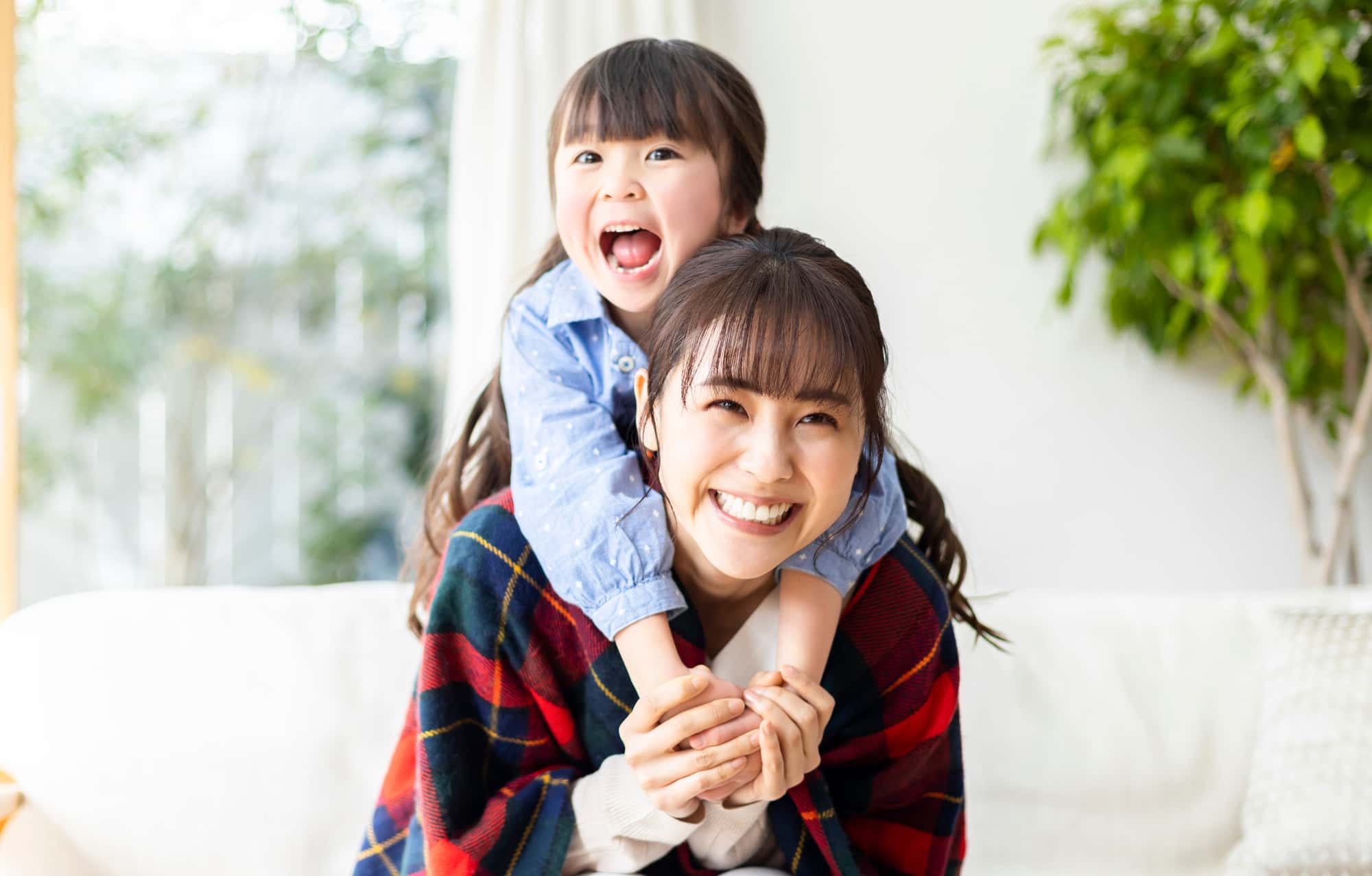 プレオルソで効果のあった子どもを背負って喜ぶ母親