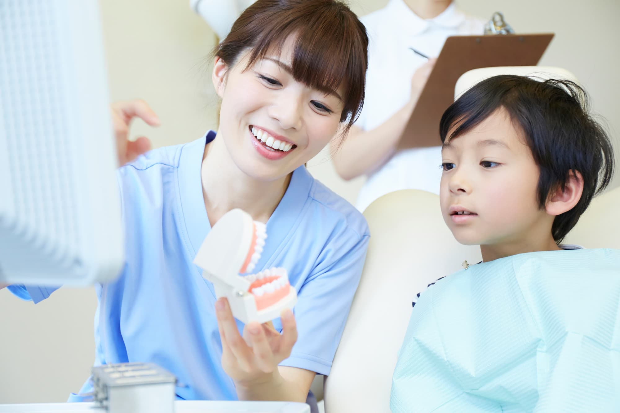 床矯正について歯の模型を使って子どもに説明している歯科医