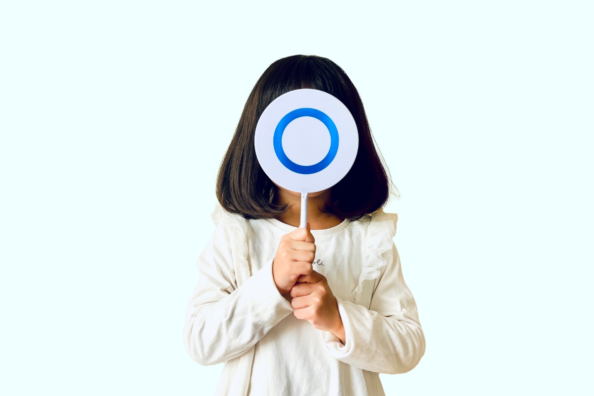 小児矯正が1期のみで終わるとマルマークを顔の前に掲げる子ども